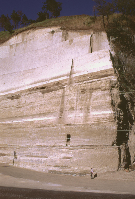 Thick sequences of tephra from Amatitlán caldera are exposed in roadcuts in the Guatemala City area, note INSIVUMEH geologist Otoniel Matías for scale at the lower right. This exposure is located south of the capital city, along the road to Palin. Major explosive eruptions from Amatitlán caldera have been dated to between about 300,000 to less than 23,000 years ago. The northern caldera rim is buried by thick pyroclastic deposits and underlies portions of Guatemala City.  Photo by Lee Siebert, 1999 (Smithsonian Institution).