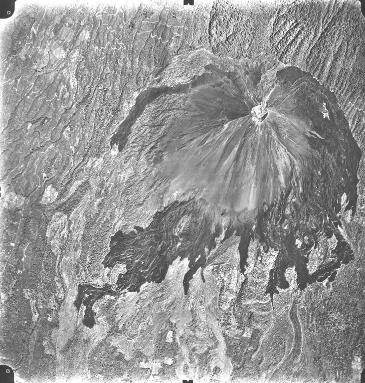 A vertical aerial photo shows the unvegetated slopes and dark-colored lava flows of Volcán de Izalco, El Salvador's youngest volcano.  It originated in 1770 CE on the southern flank of Santa Ana volcano, whose summit lies to the north (top).  Steep-sided, 650-m-high Izalco stratovolcano is truncated by a 250-m-wide crater.  The flanks of Izalco consist primarily of pyroclastic material erupted from the summit crater; lava flows mostly originated from vents on the lower flanks and were deflected southward by the slopes of Santa Ana volcano. Aerial photo by Instituto Geográfico Nacional El Salvador, 1996.