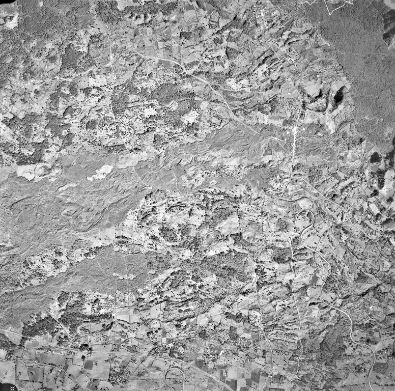 Quaternary lava flows of varying ages cover the entire 4-km-wide field of view in this aerial photo of an area NW of Jalapa.  Several lobes of the sparsely vegetated Toxtlacuaya lava flow extend across the center of the photo.  The northernmost lobe joins with the darker-colored Río Naolinco lava flow at the upper right.  Both of these flows were erupted about 900 years ago from El Volcancillo, a vent on the NE flank of Cofre de Perote.  The Toxtlacuaya flow overlies older flows from the Central Cone Complex and still older flows at the bottom from Cerro La Joya. Aerial photo by Comisión de Estudios del Territorio Nacional (CETENAL), 1:25,000.