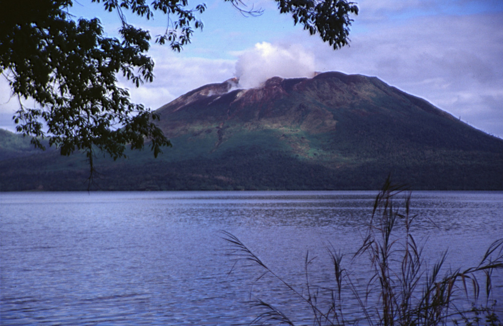 A plume rises from the active crater of Mount Garat in this view across Lake Letas, within the 6 x 9 km summit caldera of Gaua volcano (also known as Santa Maria). Three craters are located at the top of Mount Garat. The onset of eruptive activity from a vent high on the SE flank in 1962 ended a long period of dormancy. Photo by John Seach, 1999.