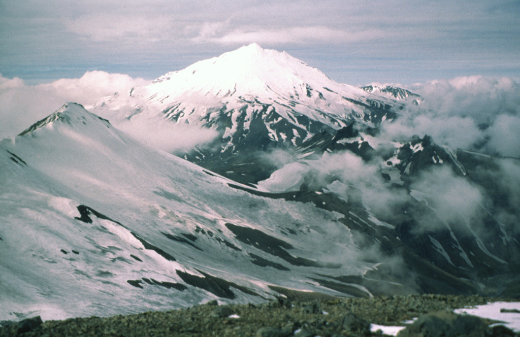 Mount Dutton near the tip of the Alaska Peninsula is seen here from the NE. Successive lava domes overlying lava flows form the summit. Dome and flank collapse during the Holocene produced debris avalanche that traveled to the west and also reached Belkofski Bay to the south.  Photo by Betsy Yount (Alaska Volcano Observatory, U.S. Geological Survey).