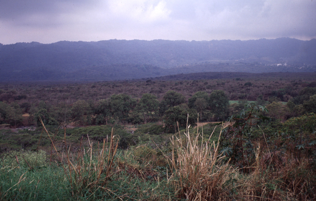 The Río Naolinco lava flow, which fills the entire valley floor in the foreground, is the most voluminous of two chemically distinct lava flows erupted from El Volcancillo on the south flank of Cofre de Perote volcano about 900 years ago. The Río Naolinco flow traveled 50 km and has an estimated volume of about 1.3 km3. This view looks south across the flow near its widest point about 25 km from the vent. Photo by Lee Siebert, 2000 (Smithsonian Institution).