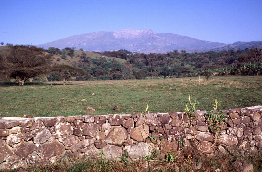The eastern side of Cofre de Perote volcano contains scarps from a series of edifice collapse events during the late Pleistocene. The youngest escarpment forms the unvegetated area below the summit in this view from just south of the town of Xico, which overlies the youngest avalanche deposit. The summit of Cofre lies 17 km to the west and 3,000 m above this location. Photo by Lee Siebert, 2000 (Smithsonian Institution).