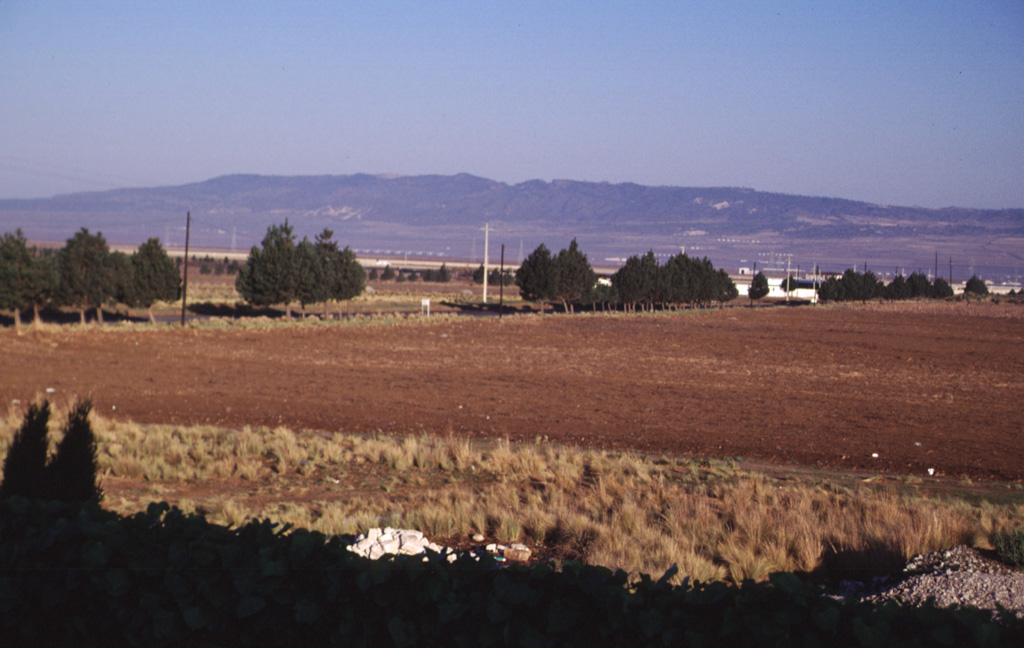 The broad ridge in the distance to the NW is Los Humeros, the easternmost of a series of large silicic volcanic centers with active geothermal systems located north of the axis of the Mexican Volcanic Belt. Eruption of the Xáltipan Ignimbrite about 460,000 years ago resulted in formation of the 15 x 21 km Los Humeros caldera. Recent eruptions at Los Humeros produced extensive basaltic lava flows; hot springs and fumarolic activity continue at Los Humeros, which has a producing geothermal field. Photo by Lee Siebert, 2000 (Smithsonian Institution).