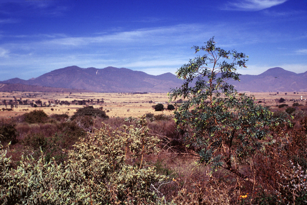 The eastern side of the Volcán el Cántaro complex, seen here from Volcán Apaxtepec, a cinder cone NE of Nevado de Colima volcano, rises above the floor of the Colima rift zone.  Cántaro is the oldest and northernmost volcano of the Cántaro-Colima volcanic complex, which extends south through Nevado de Colima to the historically active Volcán de Colima.  Cántaro is erosionally modified, but has many well-preserved andesitic-dacitic lava domes on its northern and eastern flanks, including Cerro el Capulín on the far right horizon.   Photo by Lee Siebert, 2000 (Smithsonian Institution).