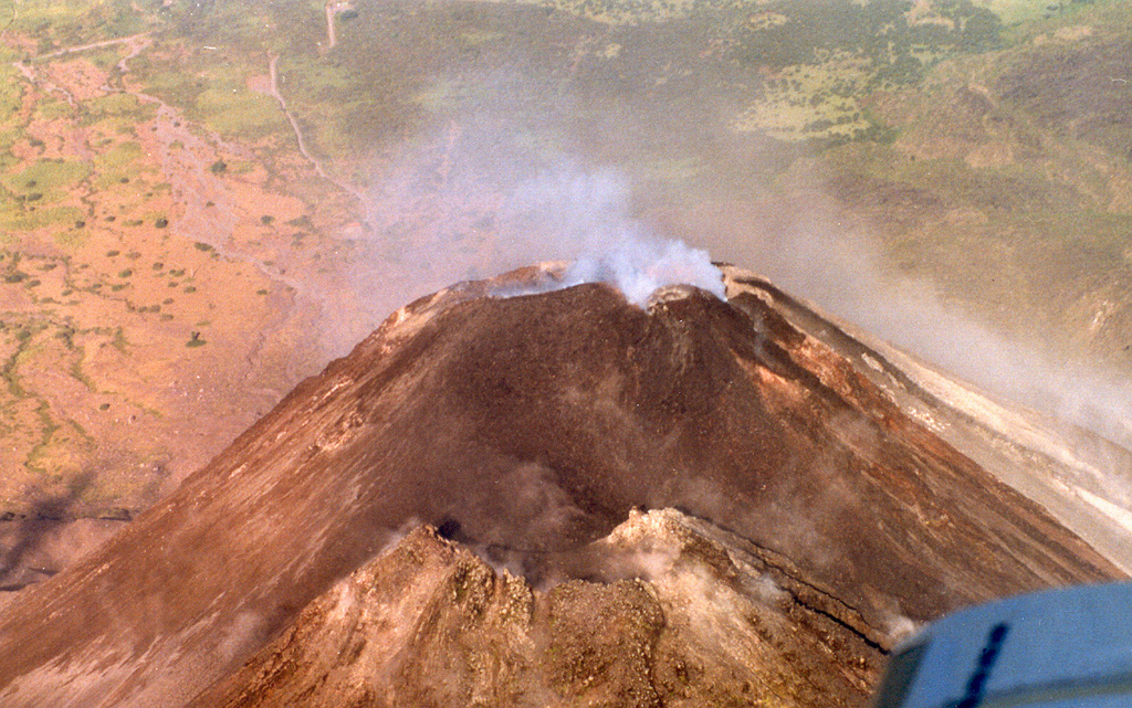 An aerial perspective of the Arenal summit area shows the older cone in the foreground and the active degassing cone in the background. Notice the newly formed small darker-colored cone on the right (north) in this 10 March 1999 photograph.  Photo by Federico Chavarria Kopper, 1999 (courtesy of Eduardo Malavassi, OVSICORI-UNA).