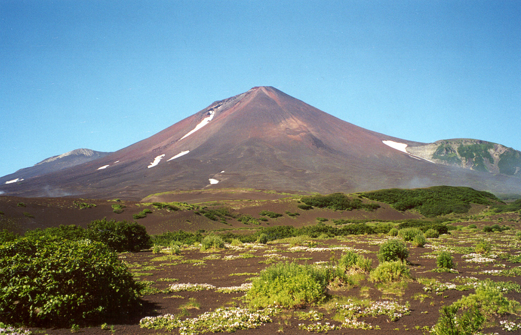 The tephra deposits in the foreground at the eastern base of Chikurachki were emplaced during a major explosive eruption in 1986. The eruption began on 18 November and reached its peak on 20-21 November when maximum ash plume heights of 10-11 km were reported. Pyroclastic flows traveled down the ESE flank. On 22 November lava flow extrusion began and continued through to 7 December, descending to 560 m elevation on the SE flank. Photo by Alexander Belousov, 2000 (Institute of Volcanology, Kamchatka, Russia).
