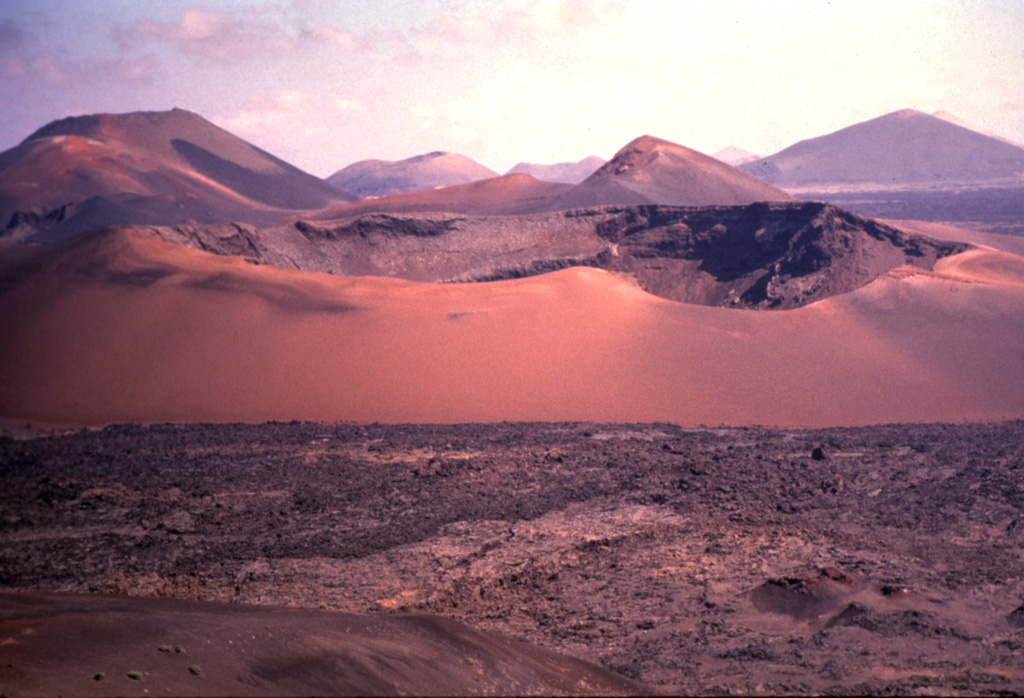 Circular Caldera del Corazoncillo (center) on Lanzarote, also known as Caldera de Fuencaliente, was active during a two-week period in September 1730, at the beginning of the 1730-36 Montañas del Fuego eruption. Lava flows effused from NE-SW-trending fissures and numerous cones (background), and reached the western side of the island over a 20-km-wide front, covering an area of about 250 km2.  Photo by Nicolau Wallenstein (Center of Volcanology, Azores University).