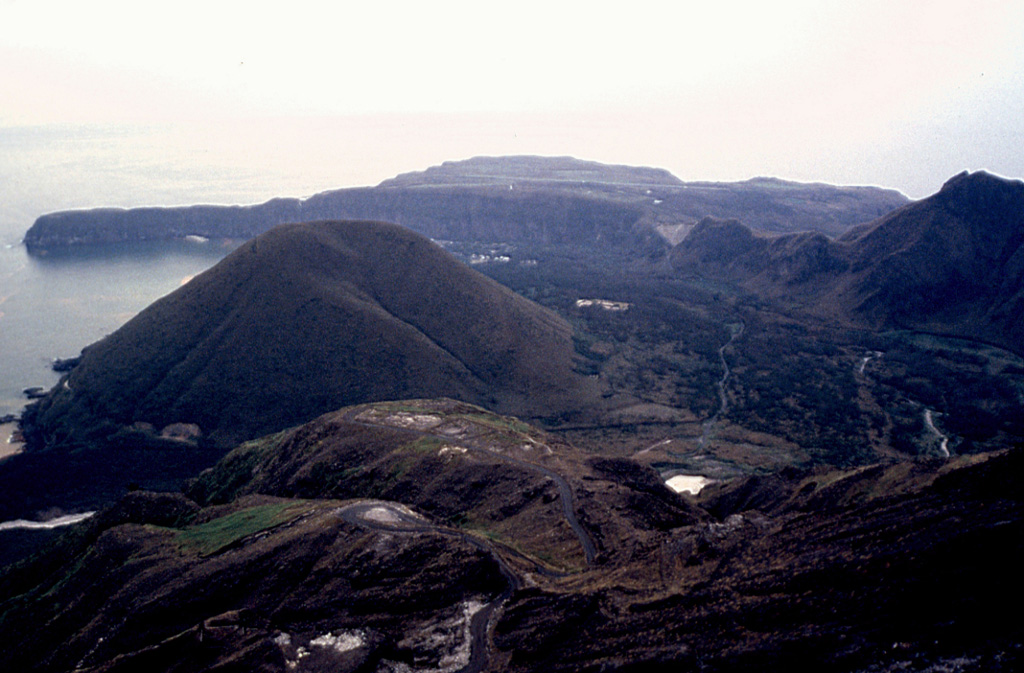 Kikai is a mostly submerged 19-km-wide caldera S of Kyushu that was the source of one of the world's largest Holocene eruptions about 6,300 years ago. Pyroclastic flows traveled across the sea for a total distance of 100 km and devastated southern and central Kyushu. This view from near the summit of the post-caldera Iwodake cone shows the W rim of Kikai caldera forming the peninsula (upper left) behind the Inamuradake scoria cone. Photo by Yasuo Miyabuchi, 1996 (Forestry and Forest Products Research Institute, Kyushu).