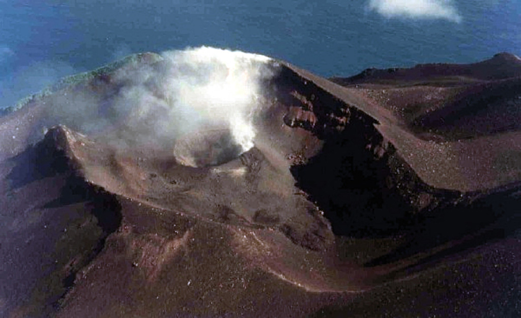 A plume is emitted from the active crater on the NW flank of Lopevi volcano in January 1999, six months after eruptive activity resumed in July 1998. The eruption took place within the elongated 1963 crater on the upper NW flank. A small lava flow erupted in December 1998 from the smaller cone onto the crater floor to the SE. Photo by J-M Bore, 1999 (Institut de Recherche pour le Développement, Vanuatu).