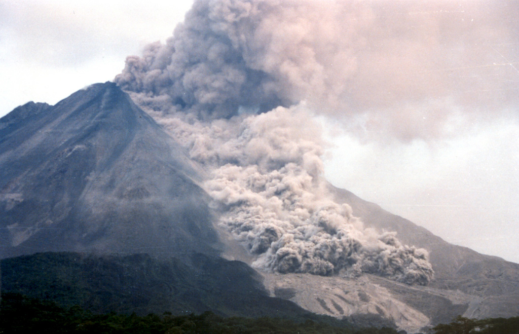 A pyroclastic flow travels down the NNW flank of Arenal on 5 May 1998, over light-colored deposits from earlier flows. As many as 23 pyroclastic flows took place during a 6-hour period that afternoon, descending the upper reaches of the Tabacón drainage basin. The pyroclastic flows reached estimated velocities of 60 km/hour.  Photo by Olger Aragón, 1998.