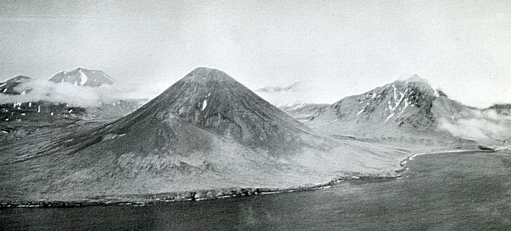 An aerial view of the SE coast of Semisopochnoi Island shows Sugarloaf peak (left-center) with a flank cone (foreground) that was the source of one of the more recent lava flows. Sugarloaf erupted outside the southern margin of an 8-km-wide caldera on Semisopochnoi. Mount Cerberus was constructed within the caldera and is on the left horizon. Pre-caldera Ragged Top is to the right.  Photo by U.S. Navy (published in U.S. Geological Survey Bulletin 1028-O).