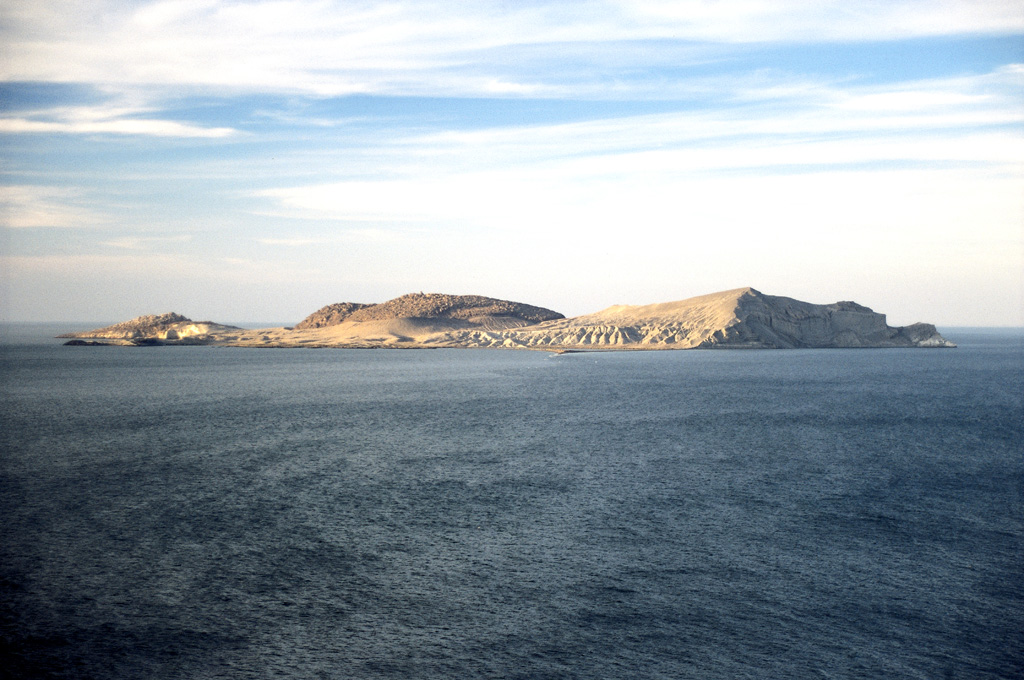 Isla San Luis, seen here from the SW with a large rhyolitic lava dome near the center, is the largest of the seven Encantada islands in the northern part of the Gulf of California. The roughly 180-m-high island lies 3 km off the eastern shore of Baja California. An older lava dome forms the NE tip of the island, and an eroded tuff ring lies at the SE tip. The lava dome seen here in the center of the island was constructed within a tuff ring and is the youngest volcanic feature. Photo by Brian Hausback, 1997 (California State University, Sacramento).