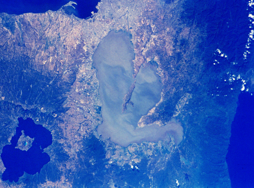 The center Laguna de Bay in the center of the NASA Space Shuttle image (N is to the upper right) is Laguna Caldera. The lake surface is only 1 m above sea level and may have formed during at least two major explosive eruptions about 1 million and 27,000-29,000 years ago. The city of Manila lies along Manila Bay at the top center, and the large caldera at the lower left is Taal. To the right is the Pacific Ocean. NASA Space Shuttle image, 1992 (http://eol.jsc.nasa.gov/).