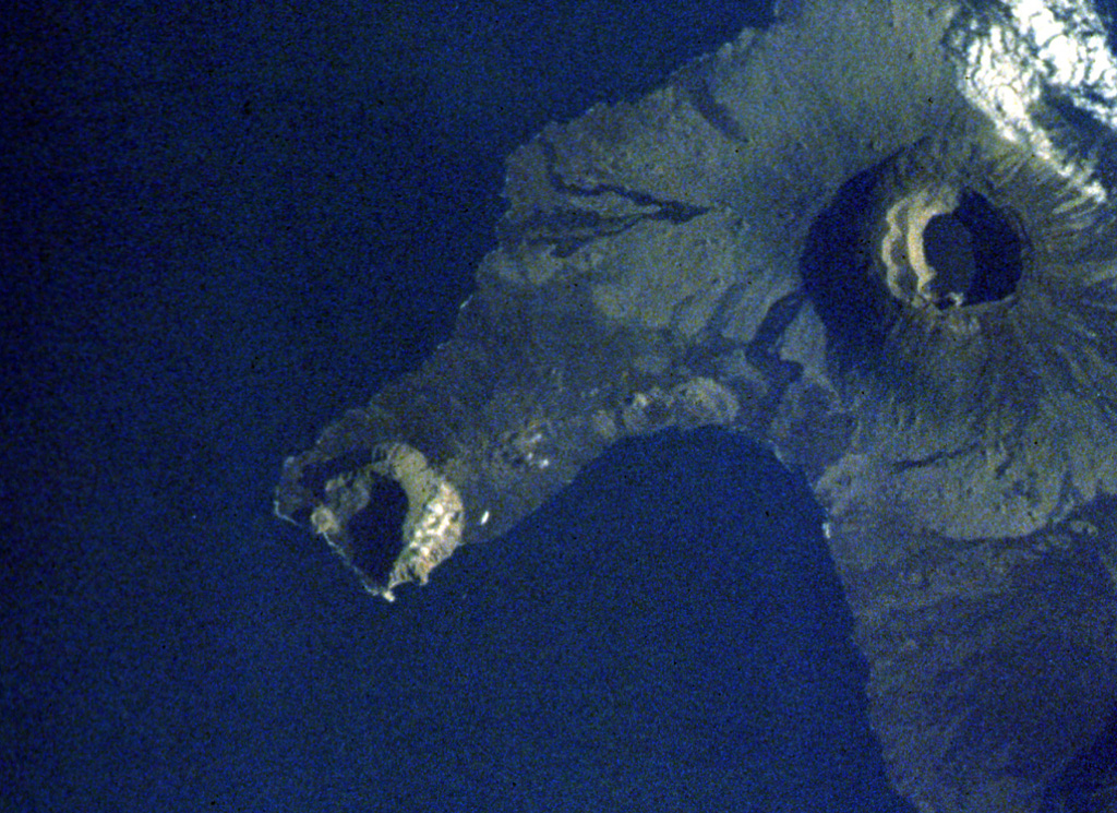 Volcán Ecuador (left center) forms the tip of a peninsula straddling the equator at the NW end of Isabela Island.  The western side of the volcano, the smallest of the six large shield volcanoes on Isabela, is breached nearly to sea level.  A line of fissure-fed vents on the outer eastern flank can be seen connecting Volcán Ecuador with Volcán Wolf (upper right).  Despite the absence of historical eruptions from Volcán Ecuador, the youthful morphology of its most recent lava flows resembles those of very recent flows on other Isabela Island volcanoes. NASA Space Shuttle image S-27-42-018, 1984 (http://eol.jsc.nasa.gov/).