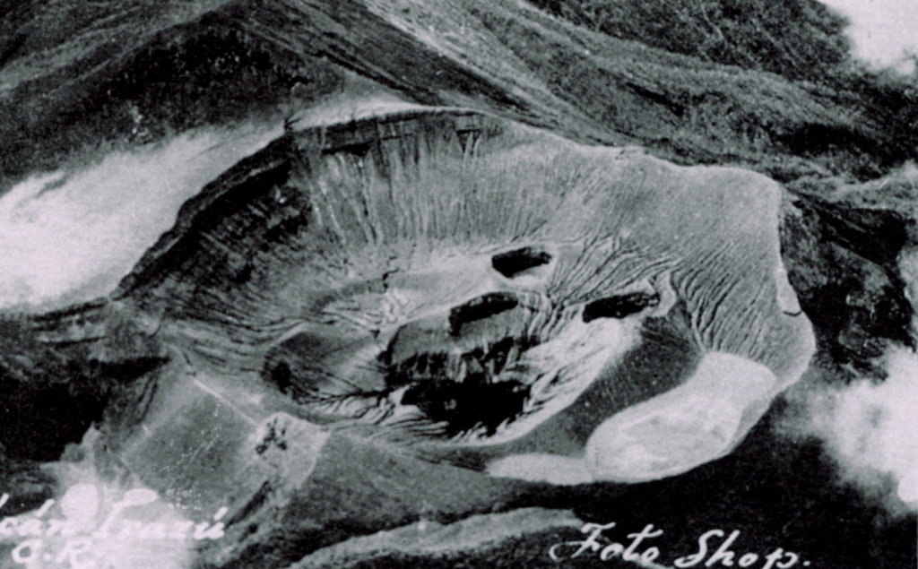 An aerial view shows the summit crater of Irazú volcano prior to the 1963 eruption, with the Diego de la Haya crater at the lower left and Playa Hermosa at the left-center. The floor of the main crater (Cráter Principal) contains several small explosion craters. The ridge on the right side of the crater floor is the remnant of the pyroclastic cone formed during the 1723 eruption. Repeated explosive eruptions during 1963-65 greatly modified the summit crater, and the individual vents seen here were merged into a single large crater. Anonymous photo (published in Alvarado, 1989).