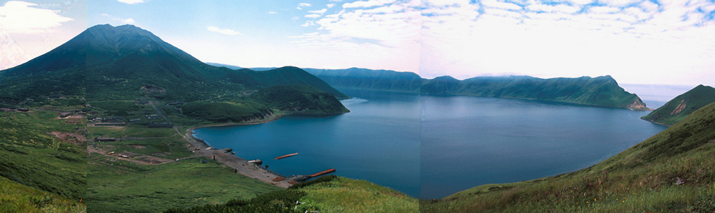 A composite panorama from the NE rim of Brouton caldera on Uratman volcano shows Brouton Bay that fills the caldera floor due to a narrow gap in the NNE rim (right). A small settlement on the NE shore of the bay lies at the foot of the cone that was constructed in the SE part of the caldera. The 7.5-km-wide caldera formed during the Pleistocene. Photo by Yoshihiro Ishizuka, 2000 (Hokkaido University).