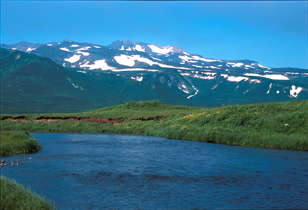 The Karpinsky Group, seen here from the south, consists of three Holocene volcanic centers at the southern end of the Karpinsky Ridge in the southern part of Paramushir Island. The southern cone forms the high point of the Karpinsky massif and produced lava flows to the SE and west. The NW cone has hot springs and sulfur cones containing boiling sulfur-rich waters.  Photo by Yoshihiro Ishizuka, 2000 (Hokkaido University).