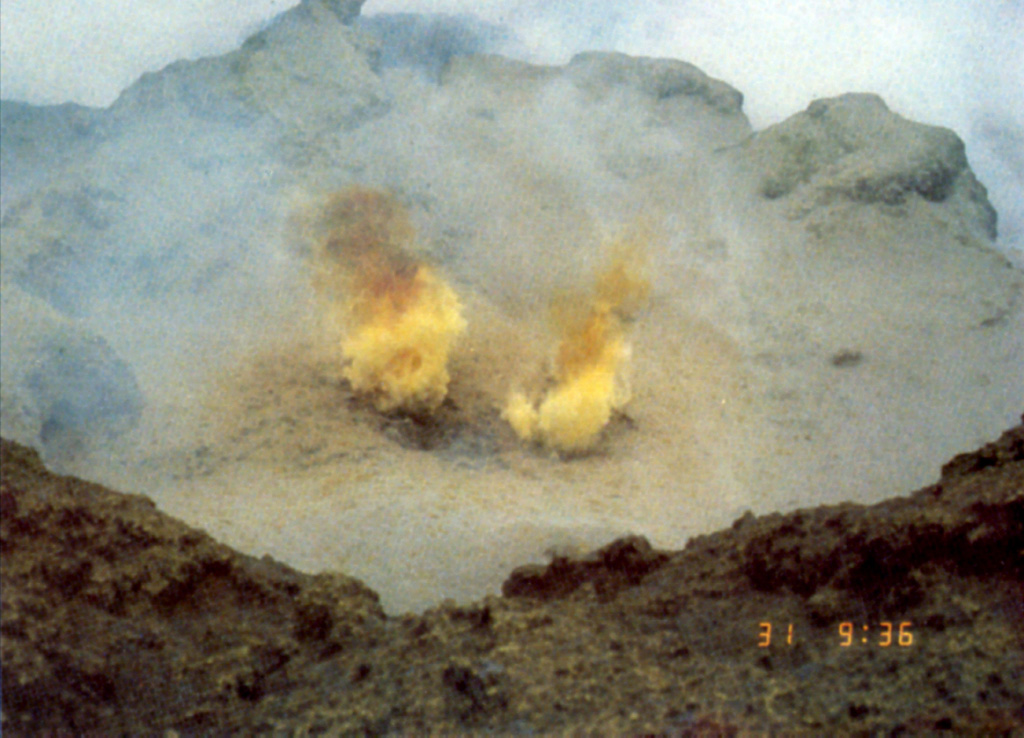 Fumarole gases at Poás are sometimes tinted yellow by the sulfur content. Sulfur clasts have been ejected during some explosive eruptions. Acidic gas plumes have damaged vegetation in the national park and surrounding areas, causing widespread devastation to coffee and other crops. An explosion on 9 April 1988 dropped acidic sulfur-rich mud on visitors, cars, and plants near the tourist overlook. Photo by Jorge Barquero (Universidad Nacional Costa Rica).