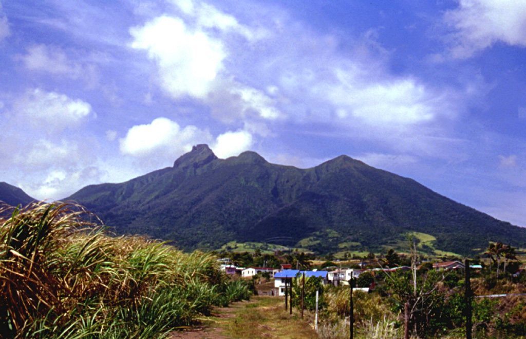The jagged eastern crater rim of Mount Liamuiga volcano, comprising the NW end of St. Kitts (St. Christopher) Island, conceals a steep-walled, 1-km-wide summit crater.  The jagged peak at left center is a lava dome on the eastern crater rim forming the high point of the island.  The most recent major eruptions at the volcano less than 2000 years ago produced pyroclastic flows and mudflows whose deposits underlie populated coastal areas.  Reports of possible historical eruptions in 1692 and 1843 are considered uncertain.  Photo by Kirstie Simpson, 2001 (Seismic Research Unit, University of West Indies).