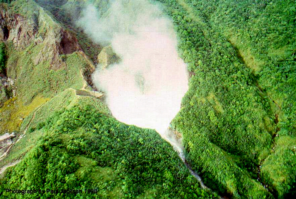 Steam rises from Boiling Lake, a geothermal area on the NE flank of Morne Watt volcano.  This phreatomagmatic explosion crater is filled by a bubbling lake about 85 x 75 m wide, with a typical depth of about 10-15 m.  Both water level and temperature have varied widely during historical time.  The lake was almost empty following the 1880 phreatic eruption, and again temporarily almost emptied in December 2004, when water levels dropped 10 m or more below the high-water mark. Photo by Paul Jackson, 1998 (Seismic Research Unit, University of West Indies).