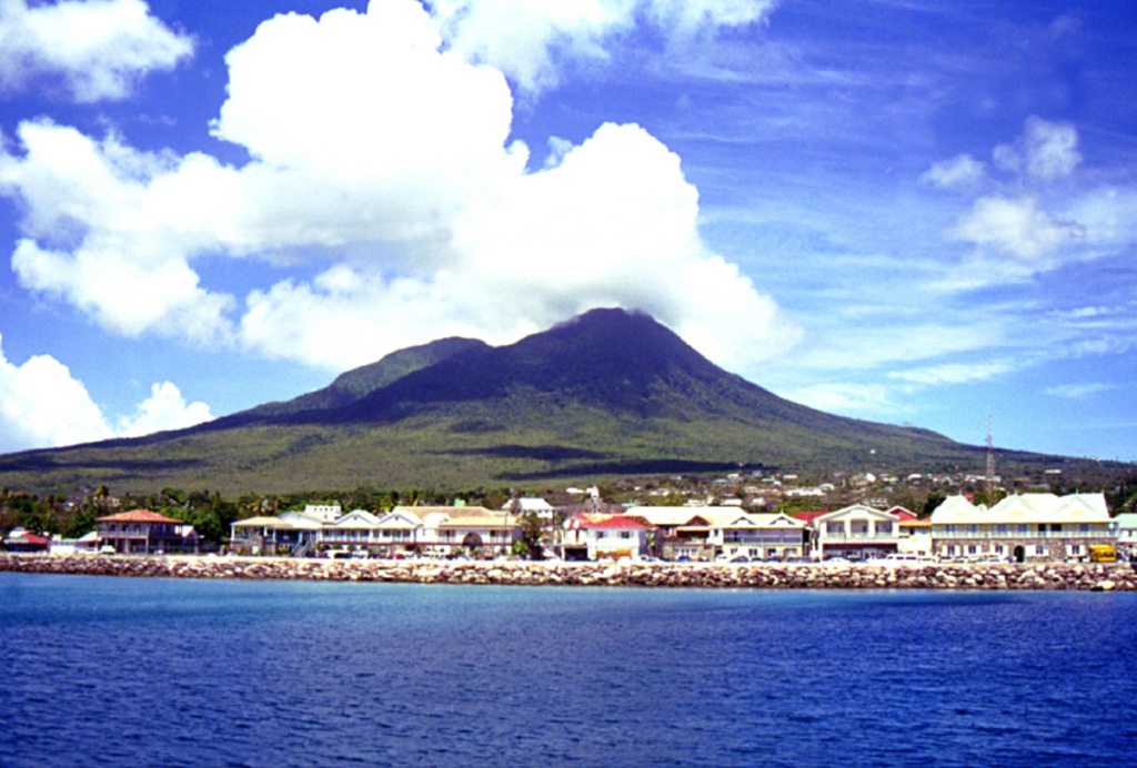 Nevis Peak volcano is seen from a ferry approaching the port of Charlestown, which lies across a narrow channel from St. Kitts Island.  The composite cone is capped by two overlapping summit craters that are partially filled by a lava dome.  Four other lava domes were constructed on the flanks of the volcano.  A small lava dome was emplaced within the inner crater in recent precolumbian time, and pyroclastic flows and mudflows were deposited on the lower slopes of the cone.      Photo by Kirstie Simpson, 2001 (Seismic Research Unit, University of West Indies).