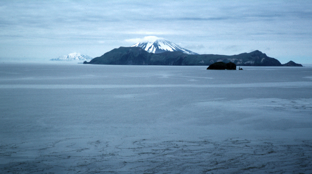 The view WNW from the western side of Little Sitkin Island includes the broad Davidof island, part of the rim of a largely submerged caldera across the right-center. The snow-capped peak behind Davidof is Segula volcano. In the background to the far left is the Kiska volcano. Photo by Steve Ebbert, 2000 (U.S. Fish and Wildlife Service).