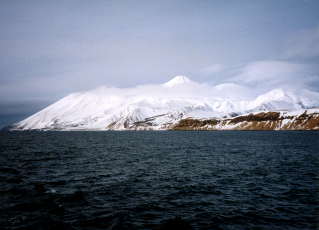 Tanaga is seen here from the SW with Cape Sajaka to the far left. The peak above the clouds is Tanaga, and Sajaka is to the left. Most Holocene eruptions originated from the central peak, which consists of two large cones constructed within a caldera with the 400-m-high rim to the SE. Photo by Steve Ebbert (U.S. Fish and Wildlife Service).