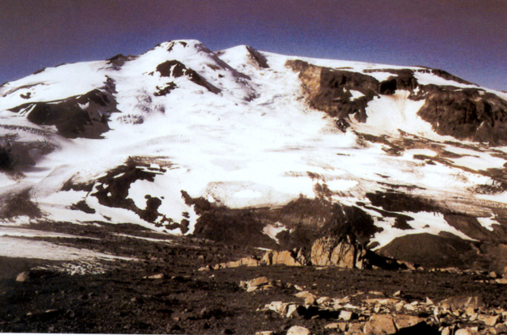 Snowy Mountain volcano lies 15 km NE of Mount Katmai. An ice-topped Holocene lava dome on the central skyline partly fills an ice-mantled scar that formed as a result of edifice collapse of the NE flank. The summit (Peak 7090) lies just behind the dome to its right. The Serpent Tongue glacier flows from the amphitheater. Photo courtesy of U.S. Geological Survey, 1999 (published in Hildreth et al., 2001).