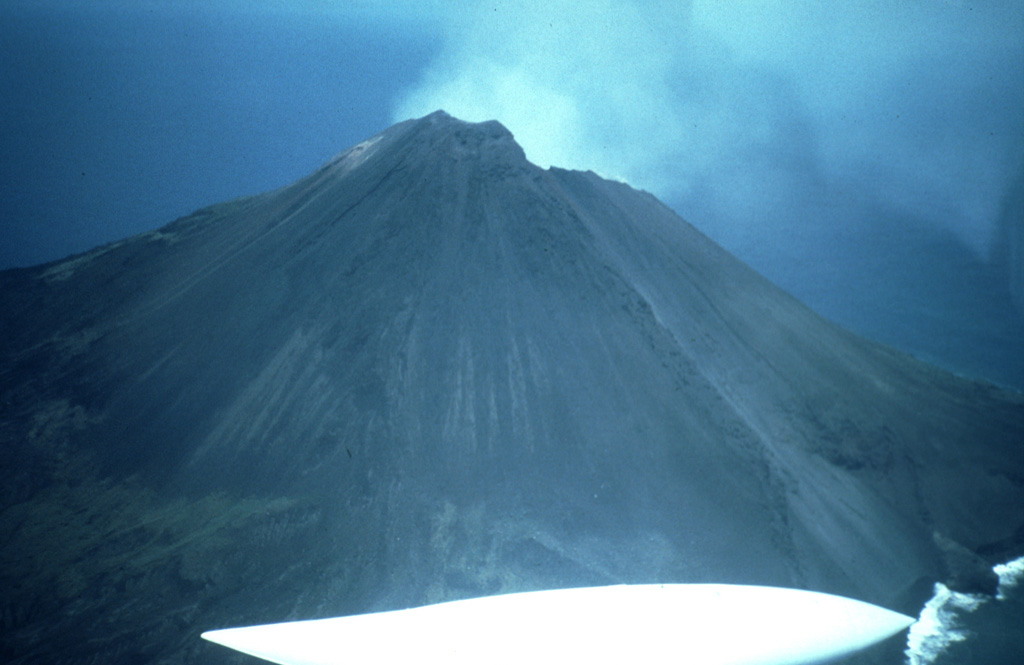 An aerial view from the SW shows the upper slopes of Asuncion in the northern Mariana Islands. It forms a circular 3-km-wide island that has had no permanent residents since the late 17th century. An explosive eruption in 1906 produced lava flows that descended about halfway down the W and S flanks. Photo by Dick Moore, 1992 (U.S. Geological Survey).