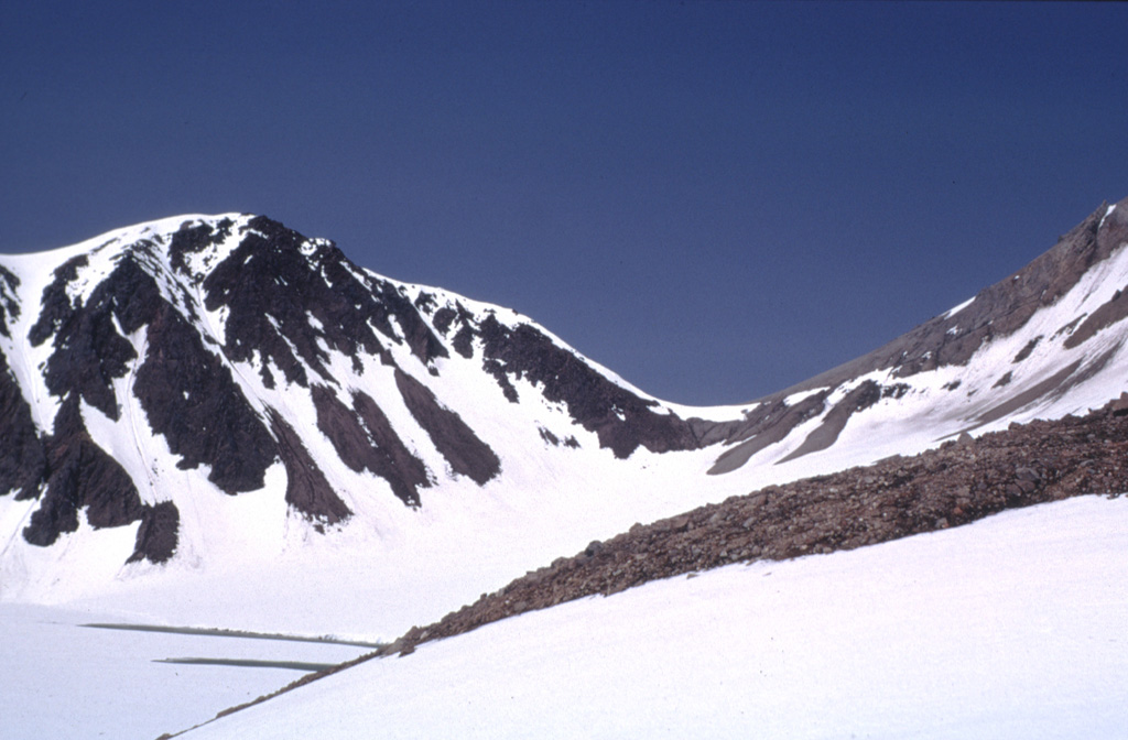 Snow-covered Knutson Lake (lower left) lies within a 1.5 x 2 km wide crater of Mount Dana. Dana is a small volcano consisting of a central dome complex surrounded by a fan of volcaniclastic debris. Lava domes are along the western crater rim and inside the crater east of Knutson Lake. A major eruption about 3,840 radiocarbon years ago produced a block-and-ash flow that filled valleys south and west of the crater. Photo courtesy of U.S. Geological Survey, Alaska Volcano Observatory, 1973.