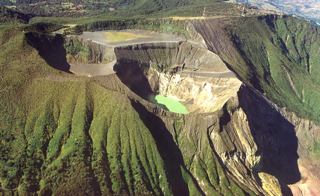 Several craters have formed at the summit of Irazú: the gray, flat floor of the Playa Hermosa crater, Irazú's main crater (center), and the Diego de la Haya crater (top left). A green lake fills the bottom of the main crater in this 1999 view, the source of most of Irazú's historical eruptions. Photo by Federico Chavarria Kopper, 1999.