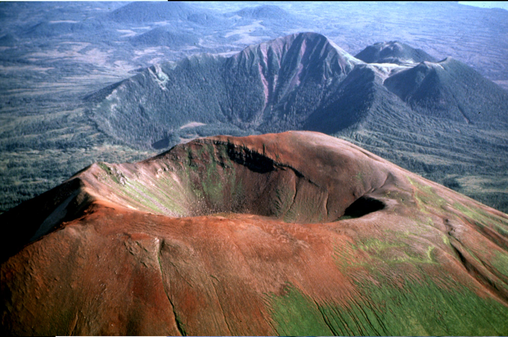 The Pleistocene-to-Holocene Mount Edgecumbe volcanic field covers about 260 km2 of Kruzov Island west of Sitka in the SE panhandle of Alaska. This aerial view shows oxidized scoria of the Edgecumbe volcano in the foreground. Crater Ridge in the background contains a 1.6-km-wide, 240-m deep caldera. And rhyolite domes (top right) The youngest eruptions from Mount Edgecumbe, the largest feature in the Edgecumbe field, are about 4,000 years old. Photo by Jim Riehle (U.S. Geological Survey, Alaska Volcano Observatory).