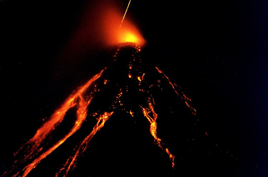 Time-lapse photograph (30 minutes) of Colima taken from a point near Suchitlán (18 km SSW) around 2300 on 26 November 1998. Incandescence appears above the summit lava dome, and lava flows and hot blocks detaching from the flows are visible down the flanks. Rapid lava extrusion had begun at 20 November 1998 following a year of small intermittent ash emissions. Long-term intermittent lava extrusion, dome growth, pyroclastic flows, and occasional strong explosions continued for several years. Photo courtesy of Claus Siebe, 1998 (Universidad Nacional Autónoma de México).