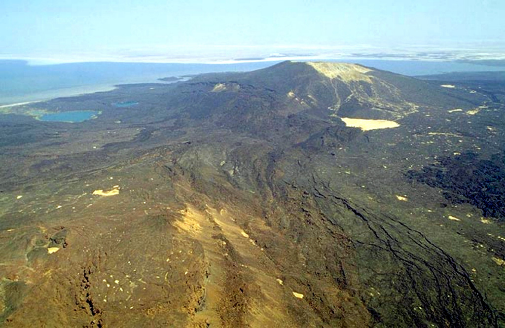 Gada Ale (upper right) is the most prominent volcano at the northern end of the Erta Ale Range. The 287-m-high volcano is seen here from the S, with two small lakes on its lower NW flank. Lake Aasale (Lake Karum) at about 116 m below sea level, is in the background. Prominent fissures (lower right) are adjacent to an uplifted salt dome (lower left). Salt diapir uplift has affected both this 2-km-wide area W of the volcano (where lava flows are uplifted as much as 100 m) and Gada Ale itself. Copyrighted photo by Marco Fulle, 2002 (Stromboli On-Line, http://stromboli.net).