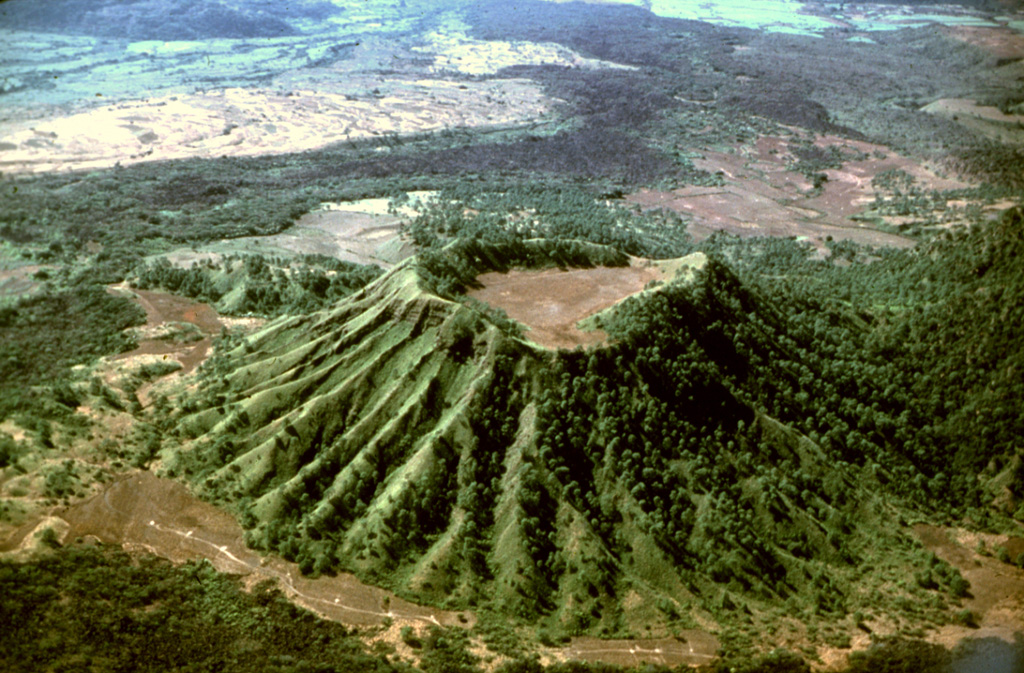 Erosional gullies have formed down the Molcajete Grande flanks, a cone on the lower NW flank of Ceboruco. This aerial view from the NE shows the forested andesite Coapan lava flow beyond the cone. The lighter-colored area just beyond the flow (upper left) is the Destiladero rhyodacitic lava flow. Photo by Jim Luhr, 1980 (Smithsonian Institution).