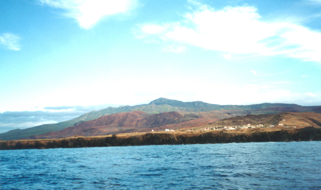 Cerro Evermann, the high point of Socorro Island, rises above a Mexican Naval camp near the southern tip of the island. Socorro lies in the Revillagigedo Islands south of Baja California. Cerro Evermann is a cone and lava dome complex that forms the summit. Rhyolite lava domes have formed along flank rifts, and silicic lava flows that were erupted from summit and flank vents have created an irregular shoreline.  Photo by Martha Marin, 1998 (Mexican Navy).