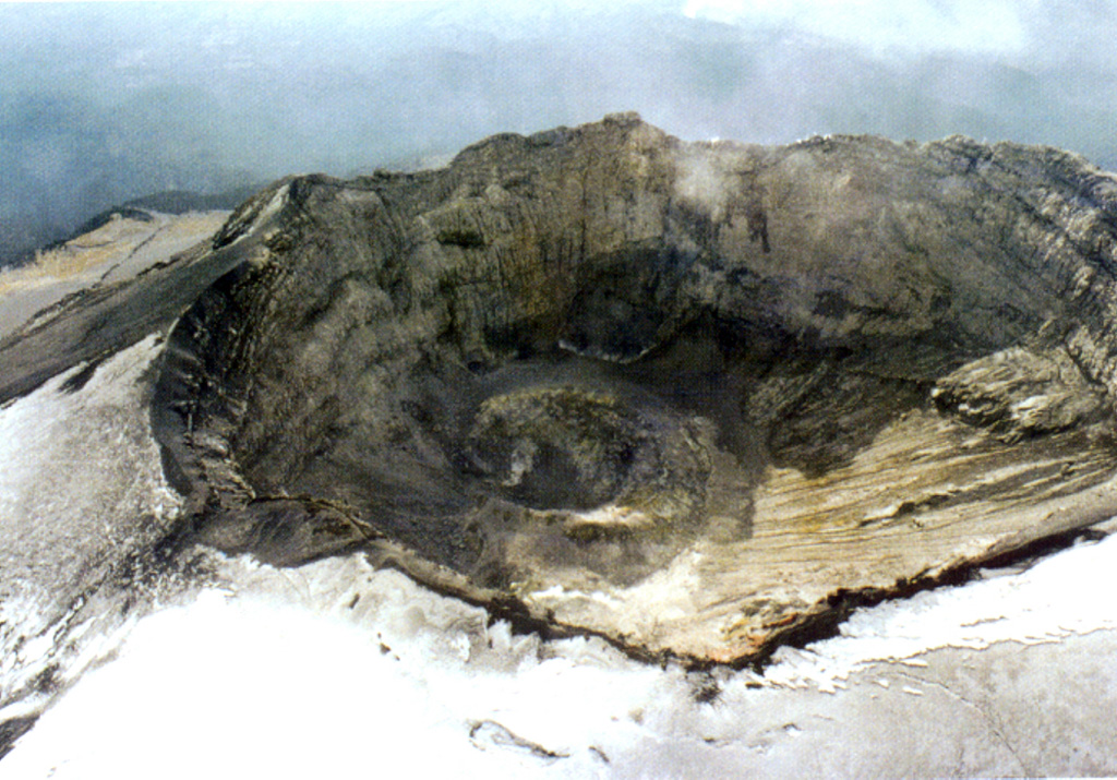 This aerial view shows the Popocatépetl summit crater in 1996, following the 1994-95 eruptive period. Subsequent activity has been both effusive and explosive, with periodic extrusion and explosive removal of lava domes emplaced on the crater floor. This aerial view is roughly from the north, with the summit out of view to the right. Photo by Hugo Delgado-Granados, 1996 (Universidad Nacional Autónoma de México).