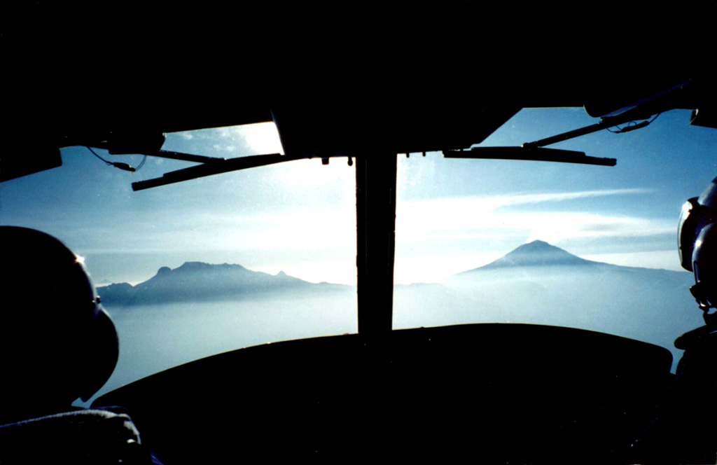A view from a helicopter heading east towards Popocatépetl (right) and Iztaccíhuatl (left) in March 2000 during a monitoring flight. Opposing winds above 6 km give the gas plume from Popocatépetl an "S" shape. The Centro Nacional de Prevención de Desastres (CENAPRED) is engaged in an active monitoring program on Popocatépetl using instrumentation to evaluate seismic, geodetic, and geochemical parameters of the ongoing eruption. Photo by Servando De la Cruz-Reyna, 2000 (Universidad Nacional Autónoma de México).