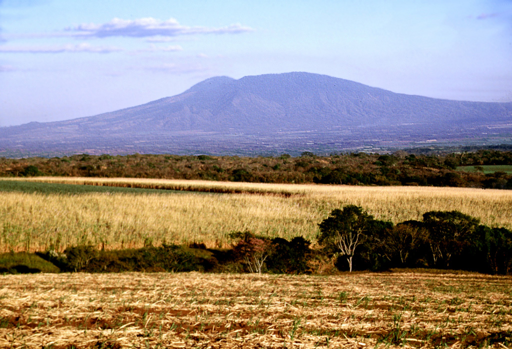 The western flanks of San Salvador rise above the Zapotitán basin beyond sugar cane fields south of Coatepeque caldera. These flanks and the rounded El Picacho peak left of the summit are part of the ancestral San Salvador volcano. The broad Boquerón edifice subsequently grew over much of the caldera rim, and lava flows traveled down the northern and southern flanks, smoothing its profile.  Photo by Lee Siebert, 2002 (Smithsonian Institution).
