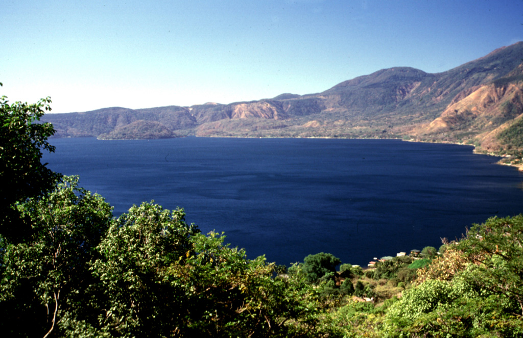 Lago de Coatepeque fills the eastern side of Coatepeque caldera. Post-caldera lava domes, including the rounded island of Cerro Grande at the far, left side of the lake, were erupted along a E-W-trending line. The rounded hill beyond the caldera and to the right is Cerro Verde. Photo by Lee Siebert, 2002 (Smithsonian Institution).