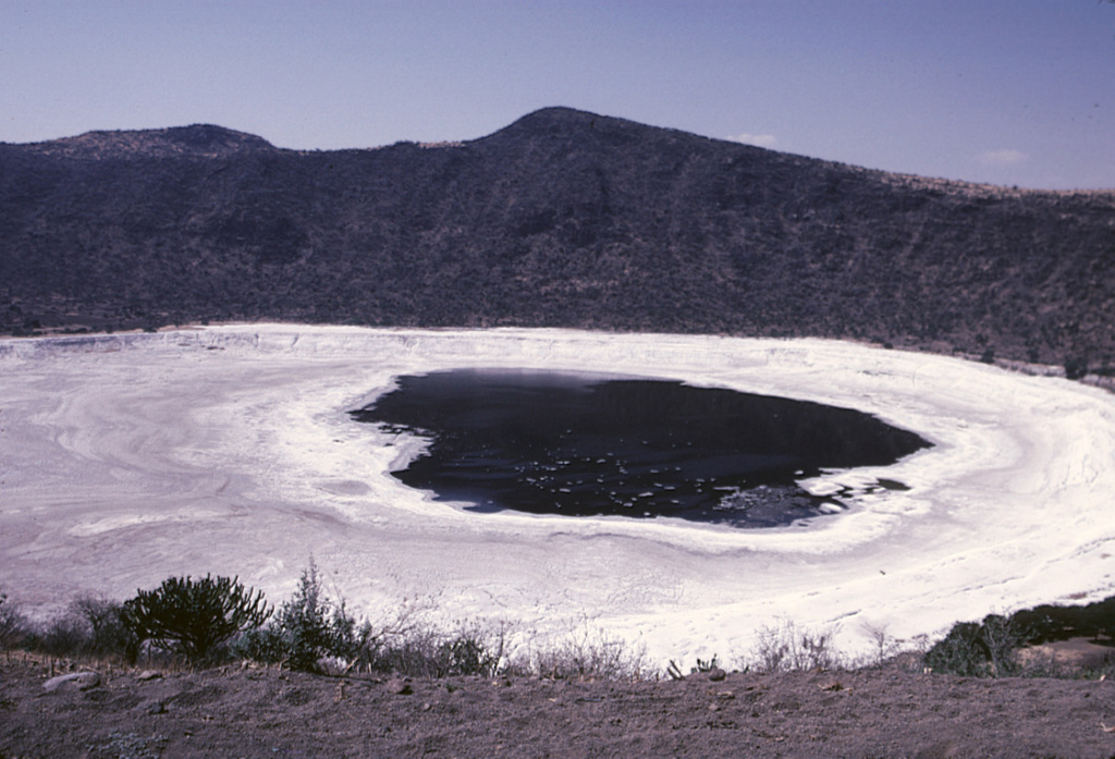 The Hoya Rincón de Parangüeo maar rises directly above the town of the same name located on the lower southern flank. A brackish lake of seasonally variable size partially fills the floor of the 2-km-wide maar, seen here from its southern rim. The high point on the northern rim rises 450 m above the crater floor. Rincón de Parangueo is part of the Valle de Santiago maar field on the NE side of the Michoacán-Guanajuato volcanic field and is about 7 km NW of the town of Valle de Santiago. Photo by Jim Luhr, 2002 (Smithsonian Institution).