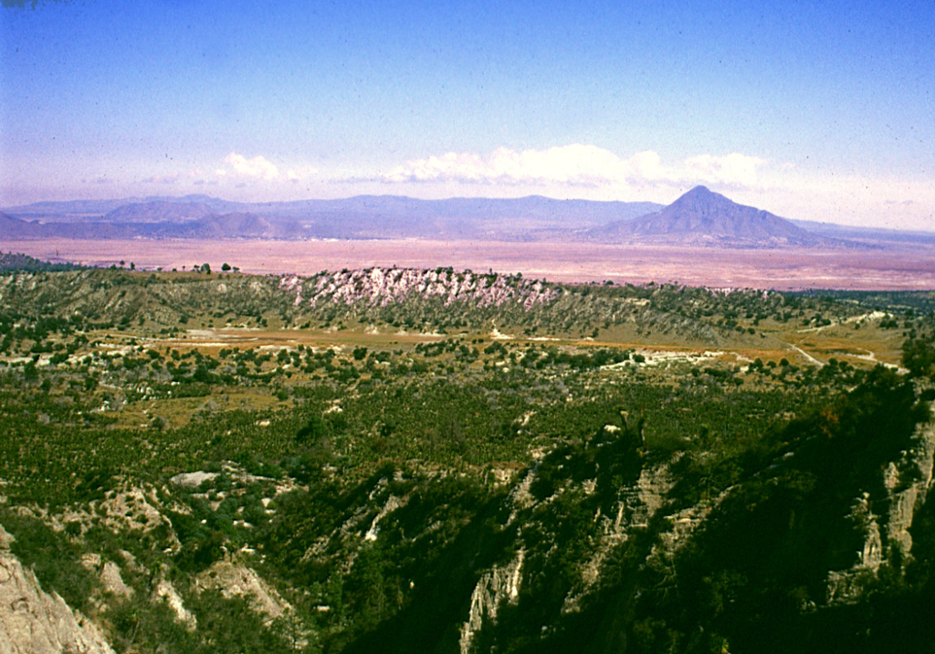 The summit of the Cerro Pinto lava dome on the western side of the Serdán-Oriental basin provides an overview of the crater floor of Cerro Xalapasco tuff cone in the foreground. Pyroclastic surge deposits associated with Cerro Xalapasco were emplaced in a relatively dry eruptive environment. The peak to the far right is Cerro Pizarro, a lava dome at the northern end of the Serdán-Oriental. The flat ridge stretching across the horizon to the north is Los Humeros caldera. Photo by Gerardo Carrasco-Núñez, 2002 (Universidad Nacional Autónoma de México).