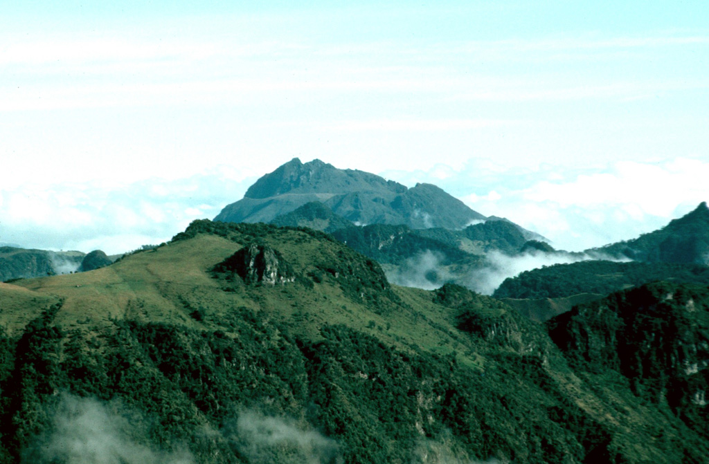 Cerro Bravo in Colombia is seen to the north from the N flank of Nevado del Ruiz. The CB1 summit dome rises above an older dome and cone complex, probably produced during the CB7-CB5 eruptive periods. Below this, the remains of the pre-Cerro Bravo volcano encompass the Pleistocene Quebrada Seca caldera. Most of the Pleistocene lava flows in the foreground are associated with Nevado del Ruiz. Photo by David Lescinsky, 1988 (University of Western Ontario).