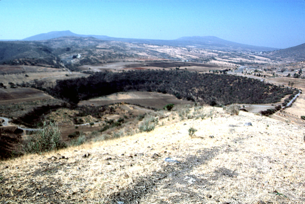 Several maars of the Michoacan-Guanajuato volcanic field are visible in this photo. The 600-m-wide Hoya Solis maar is seen from the SW rim of Hoya Blanca maar, immediately SW of the city of Valle de Santiago. The rim of Hoya de Cintora maar lies beyond Hoya Solis below the far-left horizon. Photo by Jim Luhr, 2002 (Smithsonian Institution).