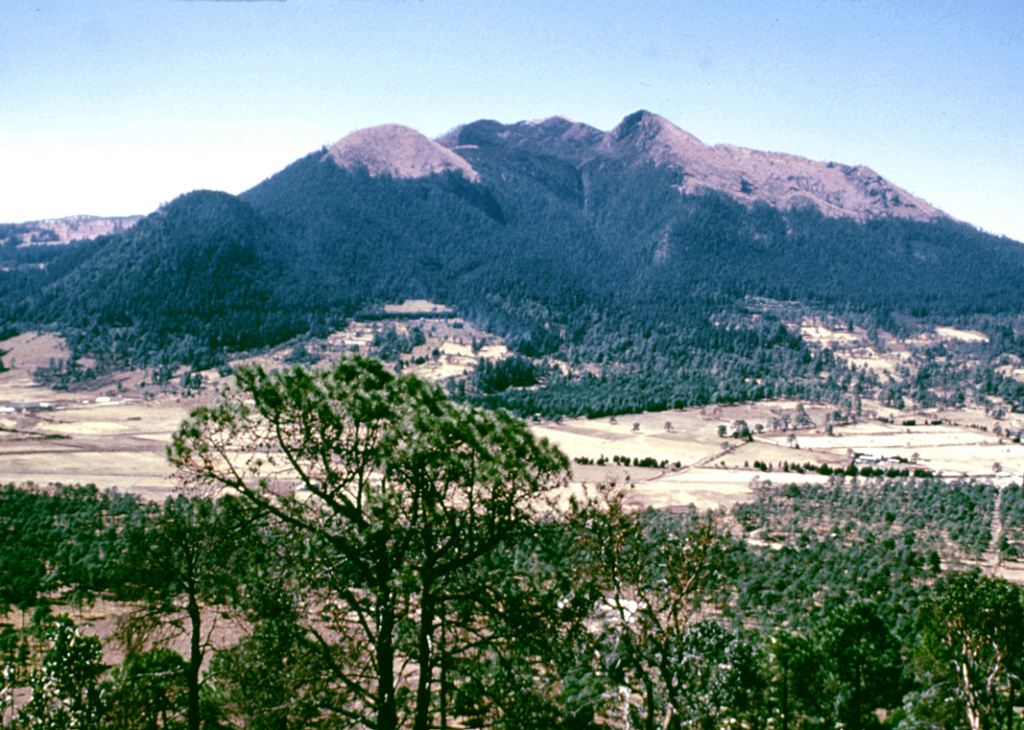 Volcán Ajusco, the highest peak of the Chichinautzin volcanic field, is seen here from the summit of the Xitle scoria cone to the NE. The Pliocene-Pleistocene Ajusco consists of lava domes surrounded by block-and-ash flows. During the Pleistocene the NE flank collapsed, producing a debris avalanche that traveled 16 km. Late-stage eruptions produced more mafic lava flows from flank vents, marking a transition to the monogenetic volcanism of the Chichinautzin volcanic field. Photo by Lee Siebert, 1998 (Smithsonian Institution).