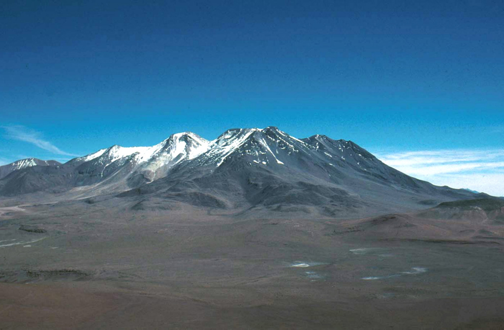 The 10-km-long, E-W-trending ridge that forms the broad summit of 6176-m-high Aucanquilcha stratovolcano consists of several overlapping volcanic edifices.  This view overlooks the southern flank of Aucanquilcha from Puquois.  The world's highest mine and permanent human habitation is located at the summit region of Aucanquilcha.  No historical eruptions are known from Cerro Aucanquilcha, but postglacial lava flows overlie moraines on the upper southern flanks.   Photo by Erik Klemetti, 2000 (Oregon State University).