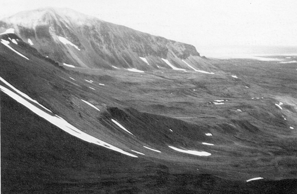 Meszah Peak of the Level Mountain volcanic complex is viewed from the east. The dark unit in the center foreground is alkali basalt. Trachytic lava flows and agglomerates form a series of benches at the base of Meszah Peak. The cliffs are composed of welded tuffs capped by thin basaltic lava flows. Level Mountain volcano is the most voluminous and most persistent eruptive center of the Stikine volcanic belt in NW British Columbia, covering an area of 1,800 km2 north of Telegraph Creek. Photo by Geological Survey of Canada (courtesy of Cathie Hickson).