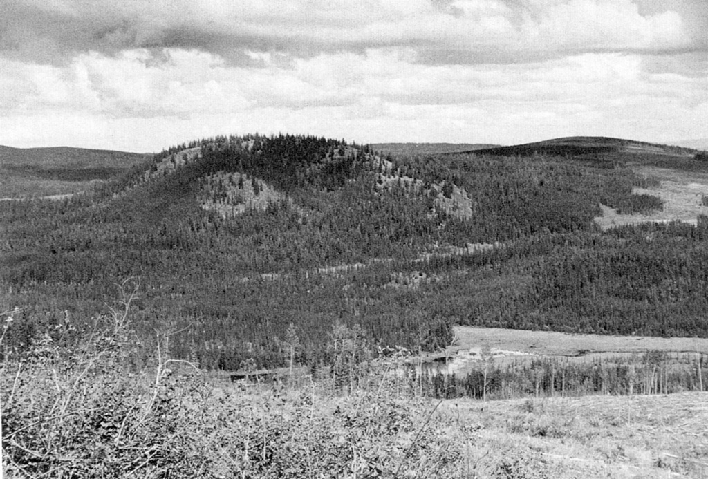 Nazko cone is the easternmost and youngest volcano of the Anahim volcanic belt in the Chilcotin-Nechako Plateau in central British Columbia. The 120-m-high cone is seen here across a valley from the SW. The central subglacial mound is partly enveloped by younger, coalescing cones that form the summit ridge. A 7,200-year-old lava flow forms the forested margin of the swamp in the middle foreground. Photo by Geological Survey of Canada (courtesy of Cathie Hickson).