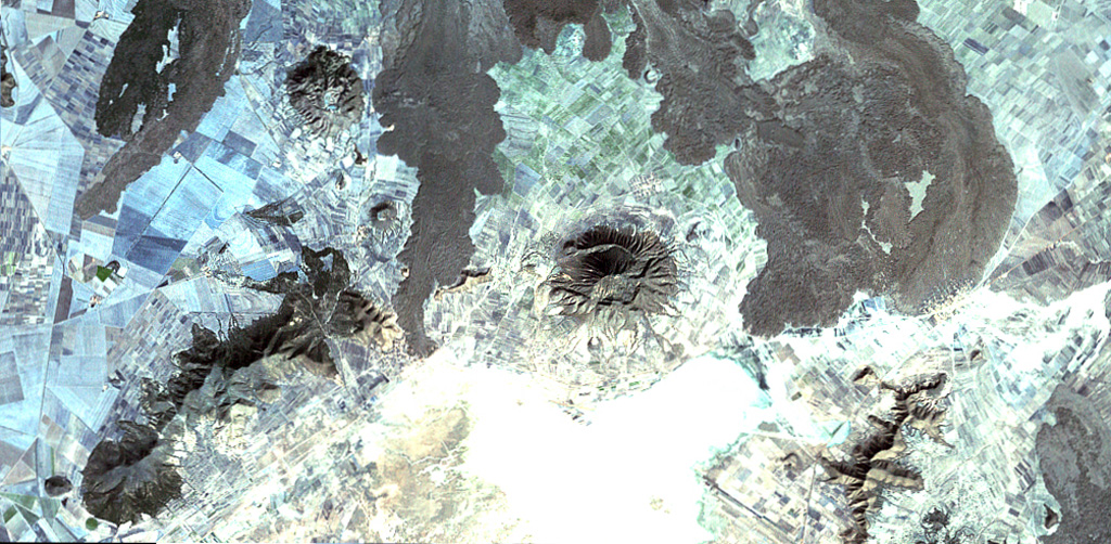 The fresh-looking lava flows at the top of the image were erupted from Los Humeros caldera (just out of view to the north). The basaltic and andesitic lava flows extend up to about 15 km from the caldera rim.  The flows have not been dated precisely, but are younger than 20,000 years and could in part be of Holocene age. The Tepeyahualco (left) and Limón (right) lava flows bracket circular 3100-m-high Cerro Pizarro lava dome (right center), the northernmost feature of the Serdán-Oriental volcanic field.   NASA Landsat satellite image, 1999 (courtesy of Loren Siebert, University of Akron).